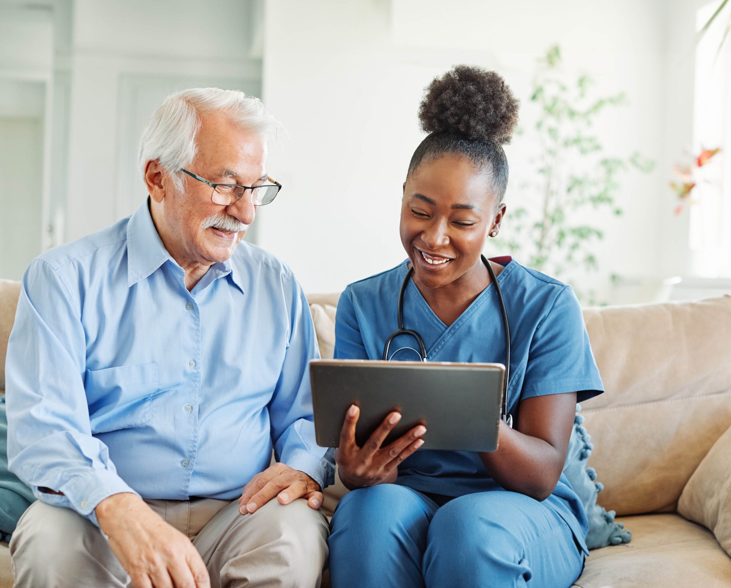 Doctor,Or,Nurse,Caregiver,Showing,A,Tablet,Screen,To,Senior